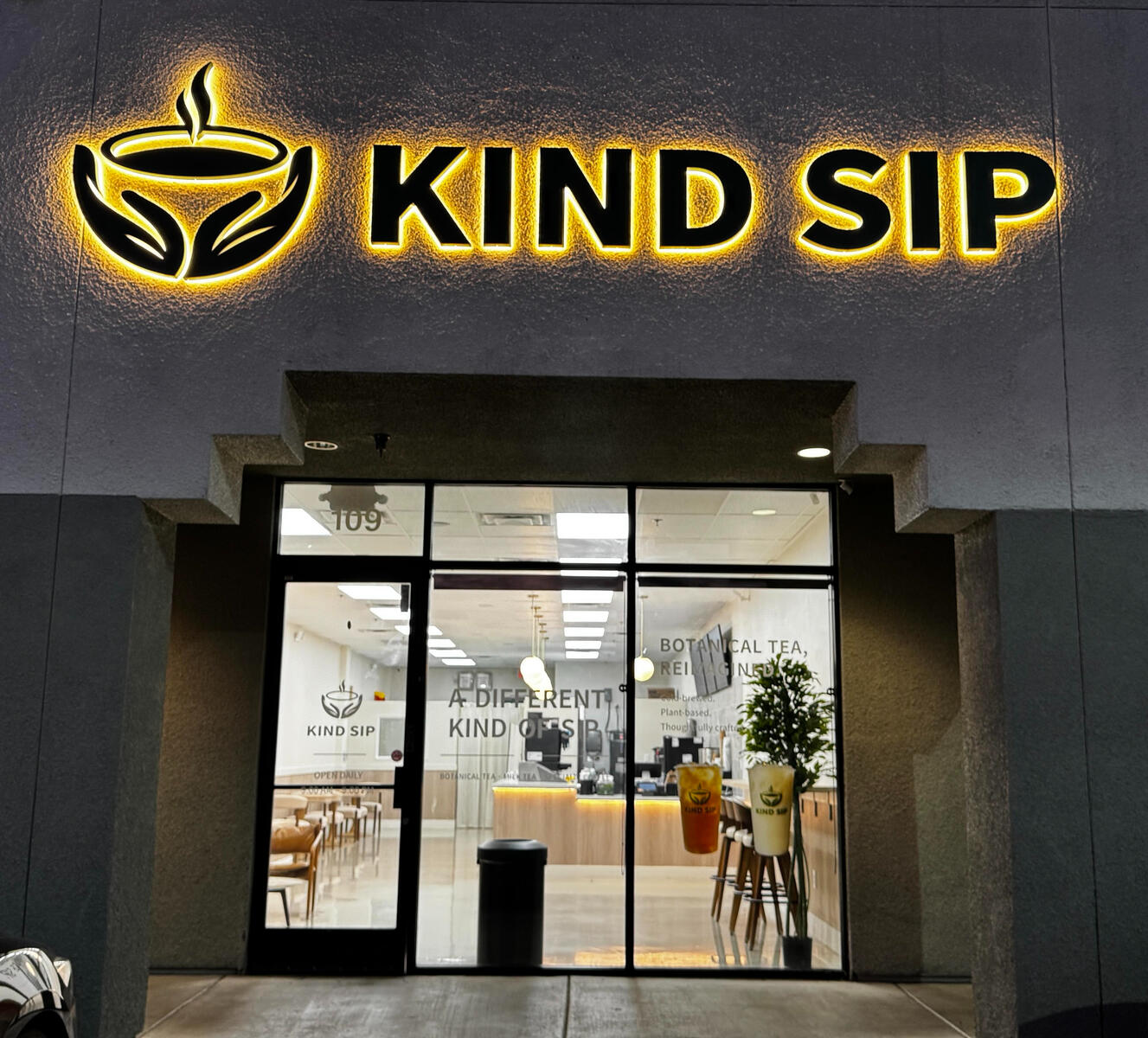 Adipiscing magna Kind Sip café storefront with an illuminated sign at night
